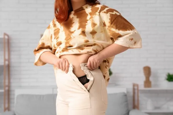 Image of woman trying to do her trousers up after pregnancy weight gain Craiglockhart
