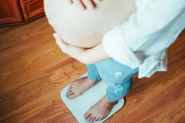 Image of woman weighing herself and experiencing weight gain through pregnancy Craiglockhart